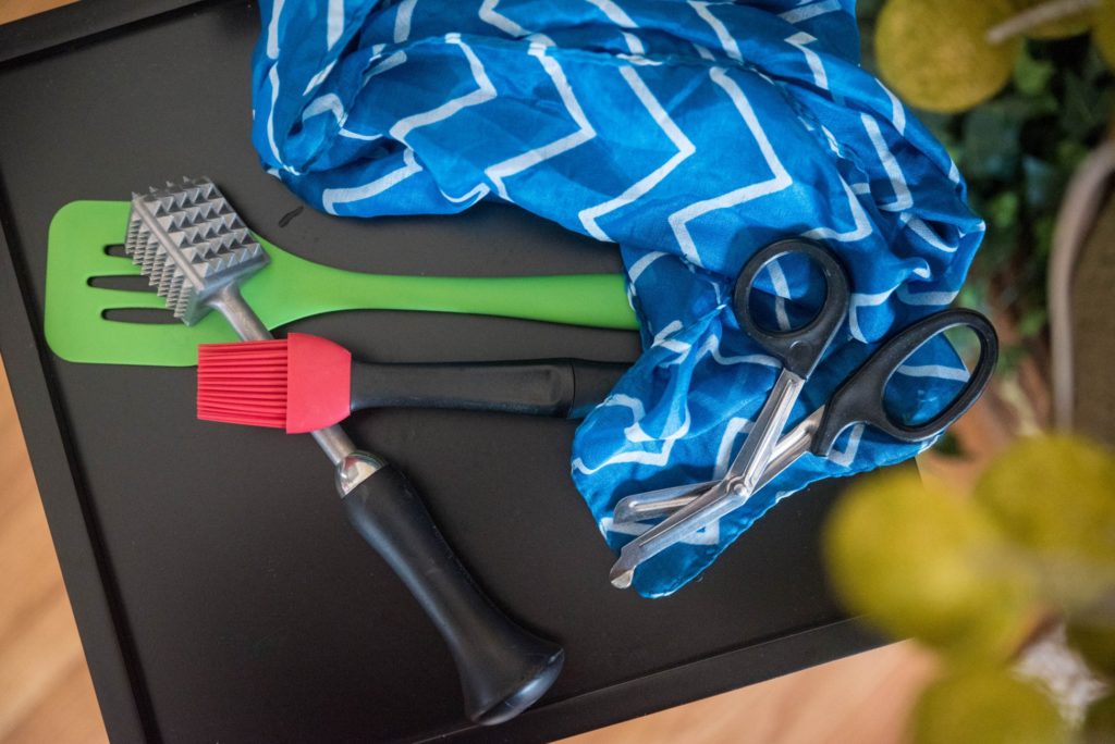 How to Find Kinky Pervertibles. A green spatula, a meat pounder, and a light blue scarf on top of a table.