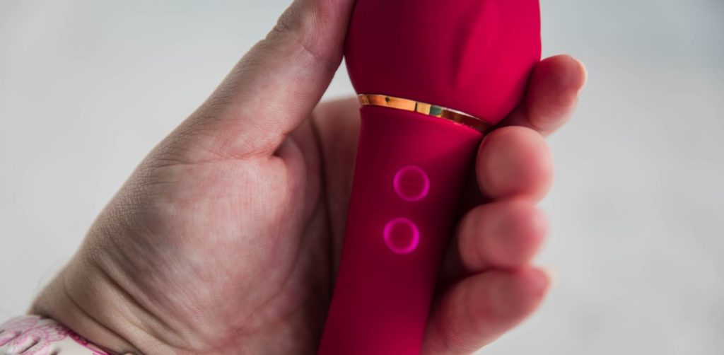 Sohimi Rose Queen Vibrator review. My hand holds the toy to with my fingers blocking the light to show the LED backlit buttons that the toy has.
