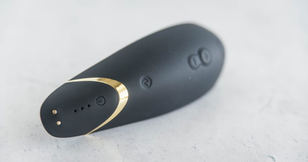 Close-up of the buttons on the Womanizer Premium. This shows the pattern button, the power button, the LED light areas, and the two magnetic ports for charging on the Womanizer Premium.
