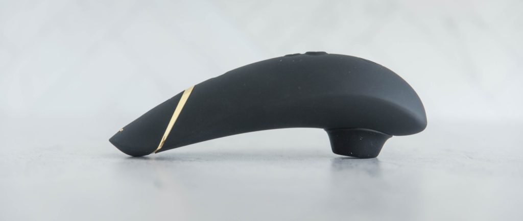 The Womanizer Premium laying out on a table. It is sitting up on its air suction tip which shows the Womanizer Premium's curved handle. This shows the shallow protruding tip of the Womanizer Premium.