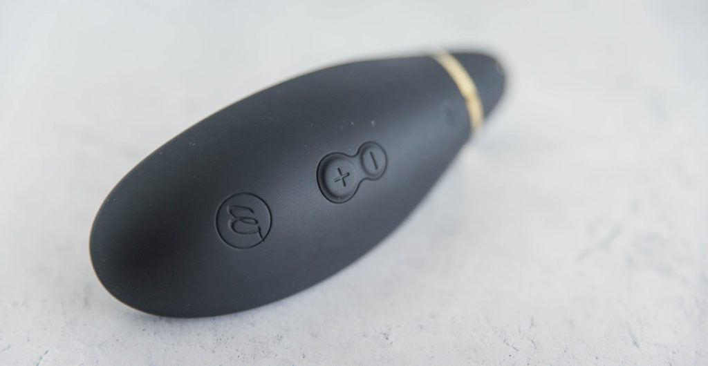 A close-up image of the buttons on the Womanizer Premium. The image clearly shows the embedded Womanizer logo along with the Plus and Minus button for controlling the suction on the toy.