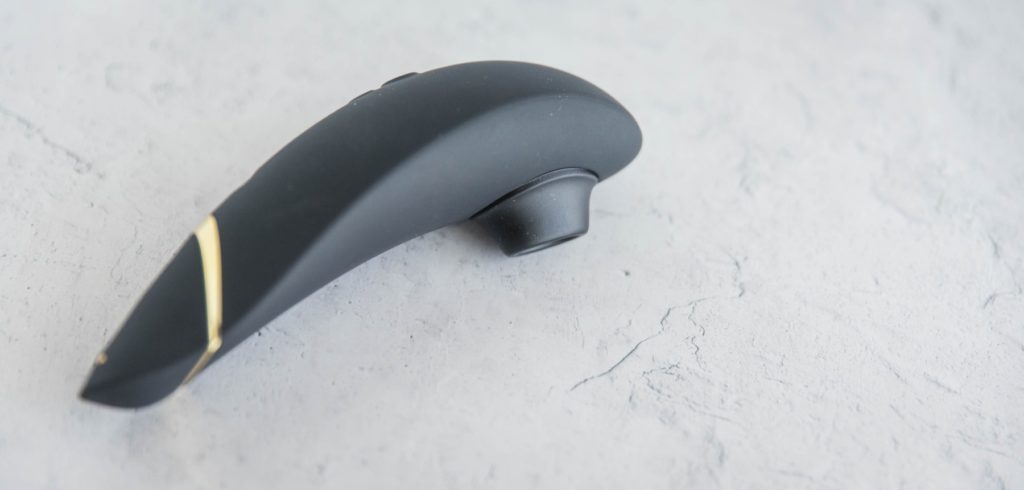 Womanizer Premium sitting out on a flat surface. The angle shows the soft curves of the air suction vibrator.