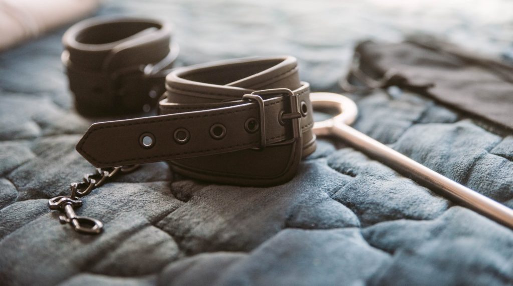 Close-up of the cuffs that are included with the Fetdom Spreader Bar. This close-up shows the soft, smooth material of the cuffs as well as a standard, non-locking buckle. The entirety of the cuffs is black with black stitching.