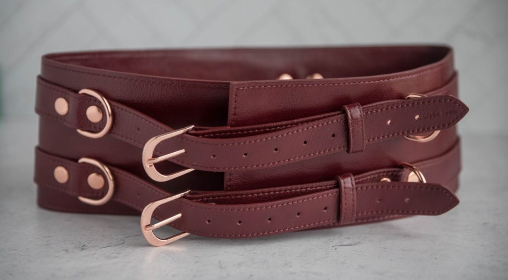 Liebe Seele Wine Red Waist Cuff Review: Close-up of the fastening belts that secure the Waist Belt onto the body. The matching rose gold hardware looks stunning against the wine red leather.