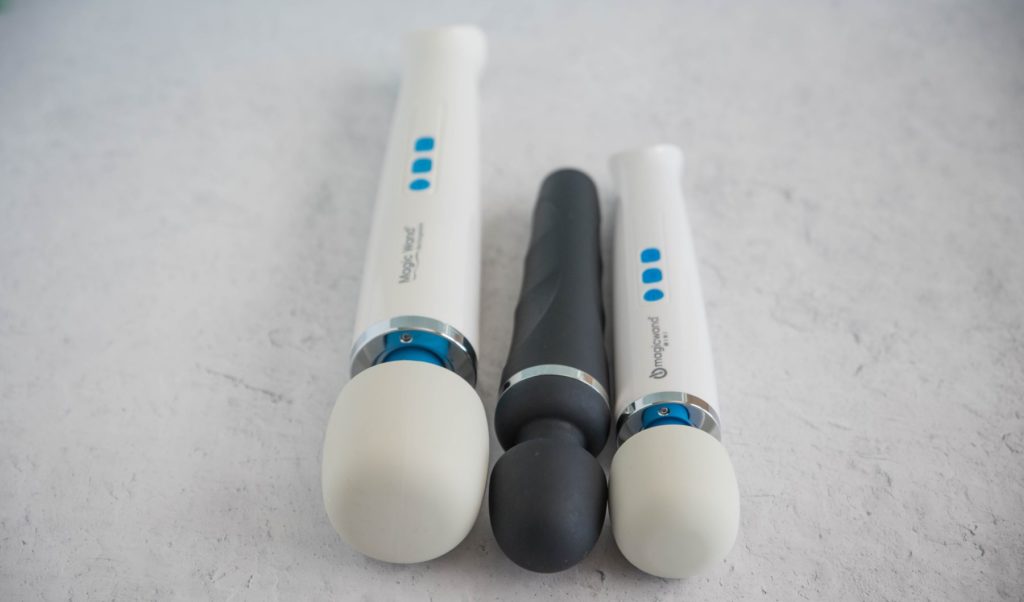 The three wand massagers next to one another with an angle focused on the various sizes of the wand massager heads. Left to right, it's Magic Wand Rechargeable, Lovense Domi 2, then Magic Wand Mini.