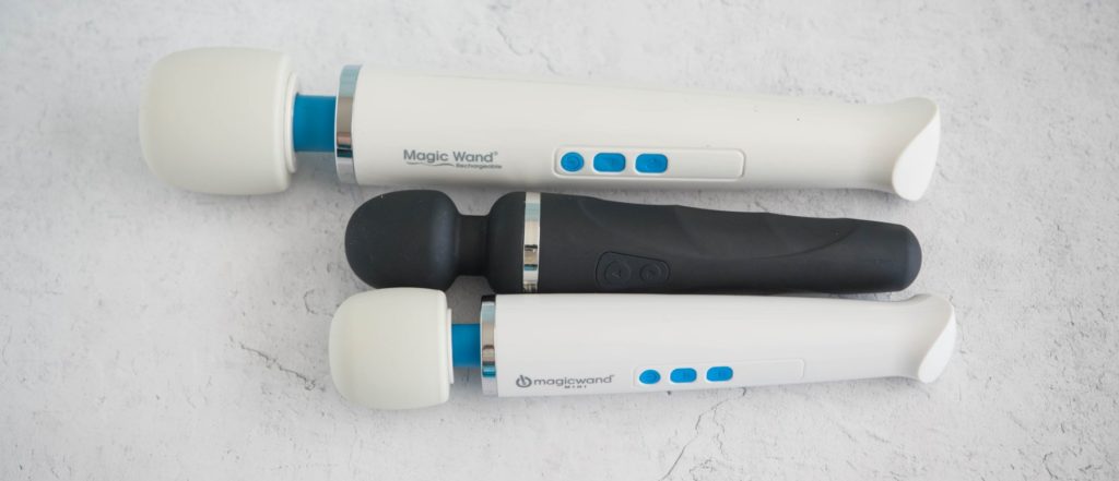 The three wand massagers next to one another with a top-down angle designed to showcase the various lengths between the three vibrators. Top to Bottom, it's Magic Wand Rechargeable, Lovense Domi 2, then Magic Wand Mini.