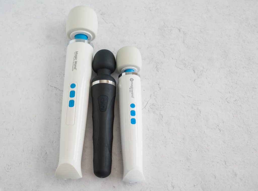 The three wand massagers next to one another with a top-down angle designed to showcase the various lengths between the three vibrators. Left to right, it's Magic Wand Rechargeable, Lovense Domi 2, then Magic Wand Mini.