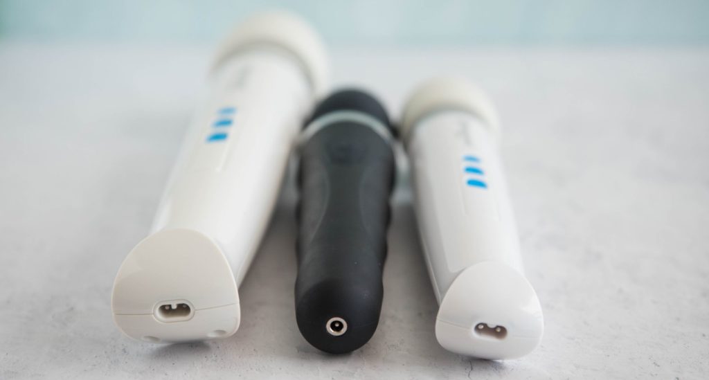 The three wand massagers next to one another with an angle focused on the various bases of the vibrators where the charging ports plug in. Left to right, it's Magic Wand Rechargeable, Lovense Domi 2, then Magic Wand Mini.