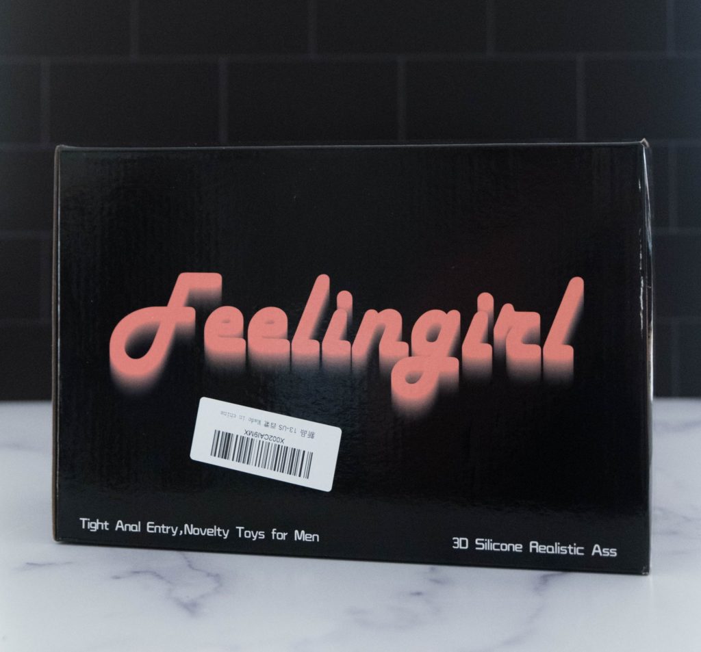Image for my Sohimi Simon review. Packaging for the sex doll with balls. It is a plain black cardboard box that looks shiny. The words "Feelingirl" are emblazoned in a large, pink font on the box.