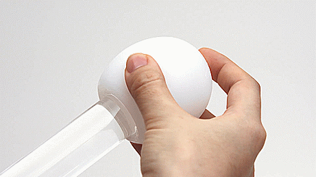 A Tenga Egg being stroked up and down a glass cylinder. It shows how the Egg expands to work for a variety of sizes.