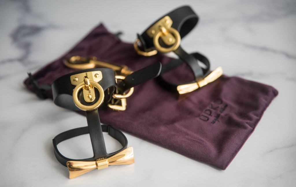 Both of the ankle cuffs sit out, propped up, on top of the purple drawstring bag that comes with the cuffs. The double-sided gold clip can also be seen in the background. UPKO Butterfly Effect Ankle Cuffs review image.