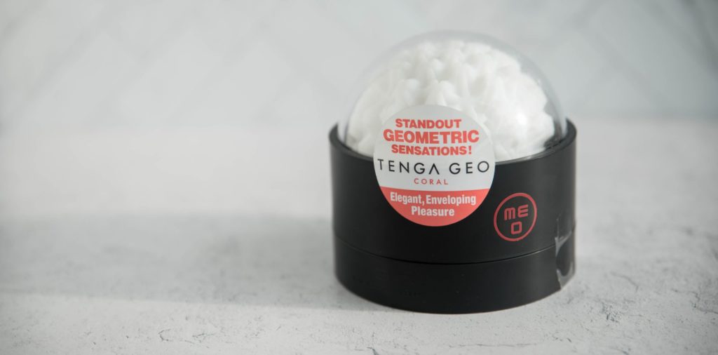 The Tenga GEO sits on the black plastic drying stand with the lid on. The lid has a "TENGA GEO" sticker on it, but it looks a bit like a spaceship dome. The star-like texture is very obvious, and the ball looks extremely plushy and soft. For my Tenga GEO review.