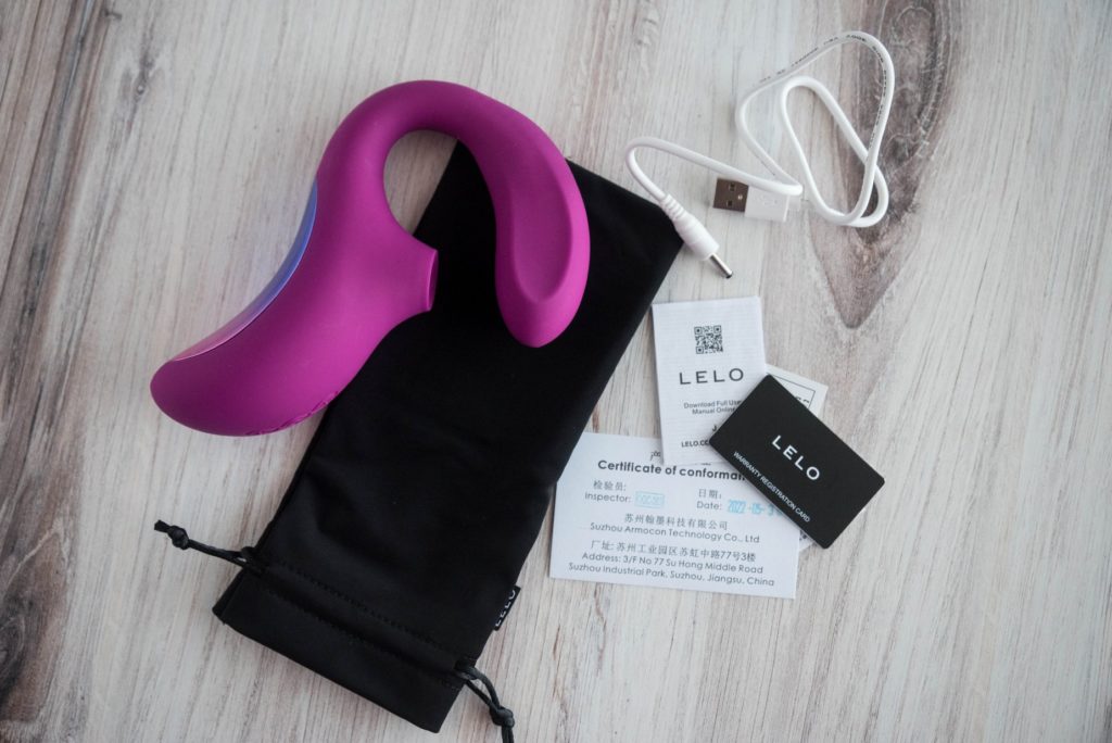 Everything that is included with the LELO Enigma Cruise in a layflat picture shot from above. There is the LELO Enigma Cruise, the charging cable, instructions, a warranty card, and a drawstring storage pouch. For my LELO Enigma Cruise review.