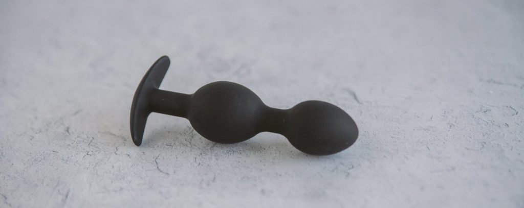 The Holly Fuck II plug lays out on a marbled surface. This side angle makes it very easy to see the two bulbs of the toy. The bulb further down the shaft is clearly slightly thicker.
