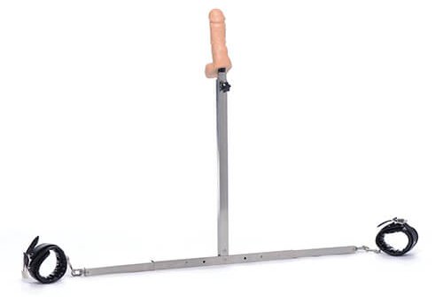 Image of the Master Series Squat Impaler. It is an upside-down T-shaped bar. On each side of the bottom of the "T" is a cuff. Sticking up on a long stick is a dildo.