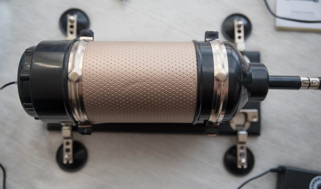 Close-up of the large metal body of the Hismith sex machine. It's rose gold and cylindrical with all of the moving parts contained within this round metal body. The four feet are folded out around it. For Hismith Sex Machine Review 3XLR version.