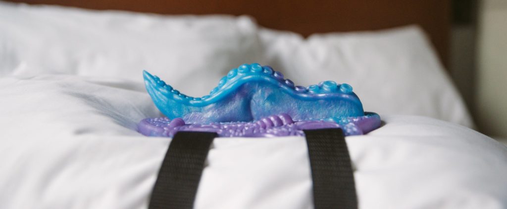 Close up of the Tentacle Grinder 2 strapped to a pillow. It almost looks like a real tentacle, and I swear I can see a tentacle vein on the side of the toy. This side angle view shows how much the toy protrudes when strapped onto a pillow. For my Uncover Creations Tentacle Grinder 2 review.