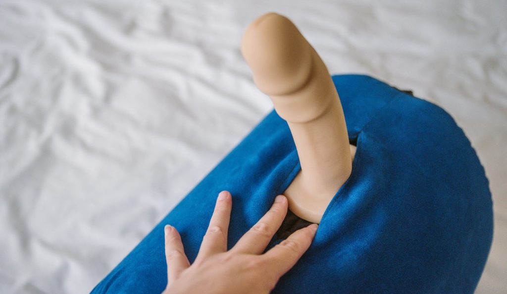 A realistic dildo is shown in the Liberator BonBon. My fingers spread the outer cover's material, showcasing how the round base is held against the shape by help of the slit in the BonBon's cover. For my Liberator BonBon Sex Toy Mount article.