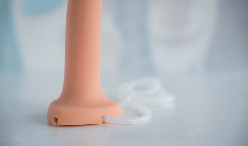 The base of the Silicone Cum Dildo. The tubing is extending out the base of the toy. An unused hole is empty next to the used hole, showing where the tubing could have routed instead. Image for my Strap-on-Me Silicone Cum Dildo review.