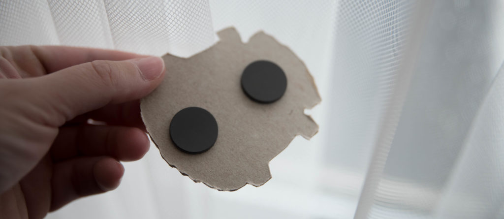 The backside of a magnet. It looks like plain cardboard with two adhesive magnets stuck on it. 