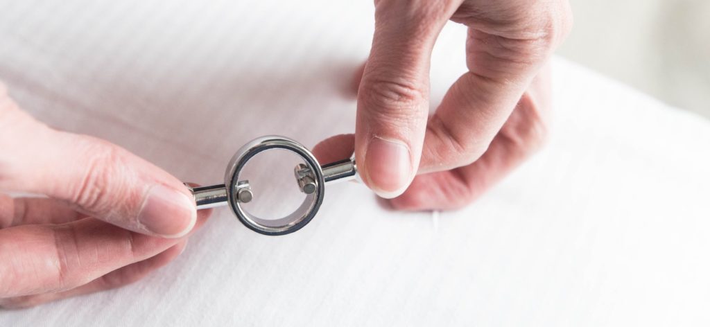 Fingers pull apart both sides of a magnetic nipple clamp. There's a wide space in the center of the clamp where the nipple would go.