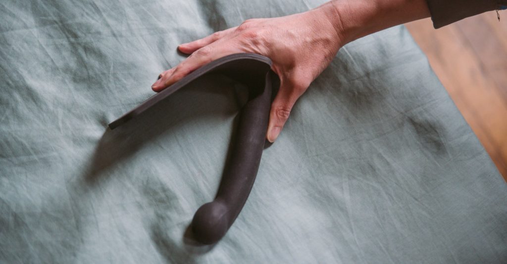 A person is bending a silicone paddle in half, showcasing how flexible the material is. The paddle folds entirely in half, in on itself. For my Everything You need to Know about Using a BDSM Paddle review.