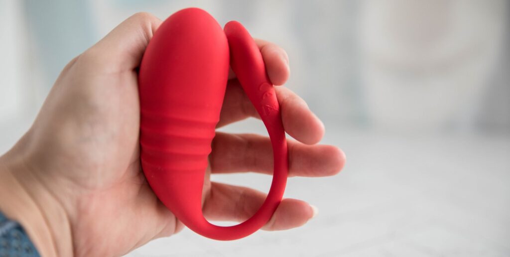 My hand holds the Lovense Vulse in it. The Vulse looks ribbed and textured, and the tail folds in easily to meet the insertable egg portion of the vibrator. For my Lovense Vulse review.