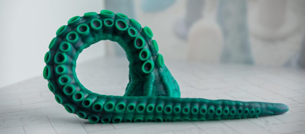 The tentacle dildo laying out in a curly-Q shape, showcasing how flexible the dildo is.