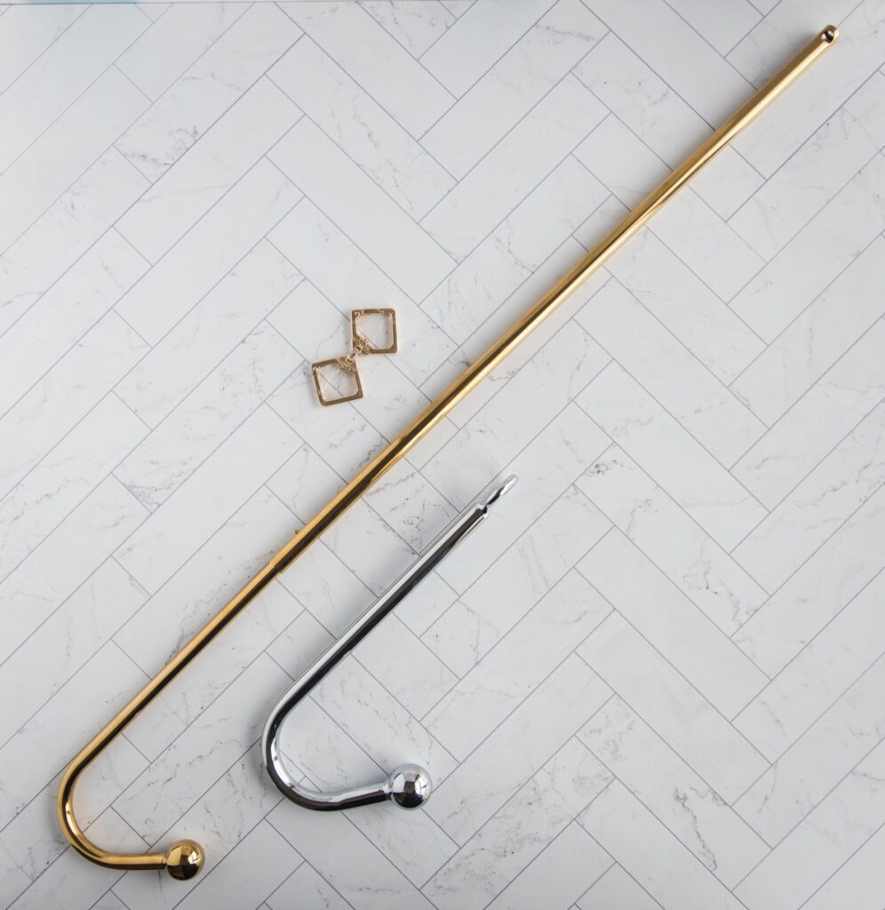 The Lockink anal hook shown sitting next to a silver, average-sized anal hook. The Lockink hook is about 3 times longer. LOCKINK Adjustable Golden Anal Hook review.