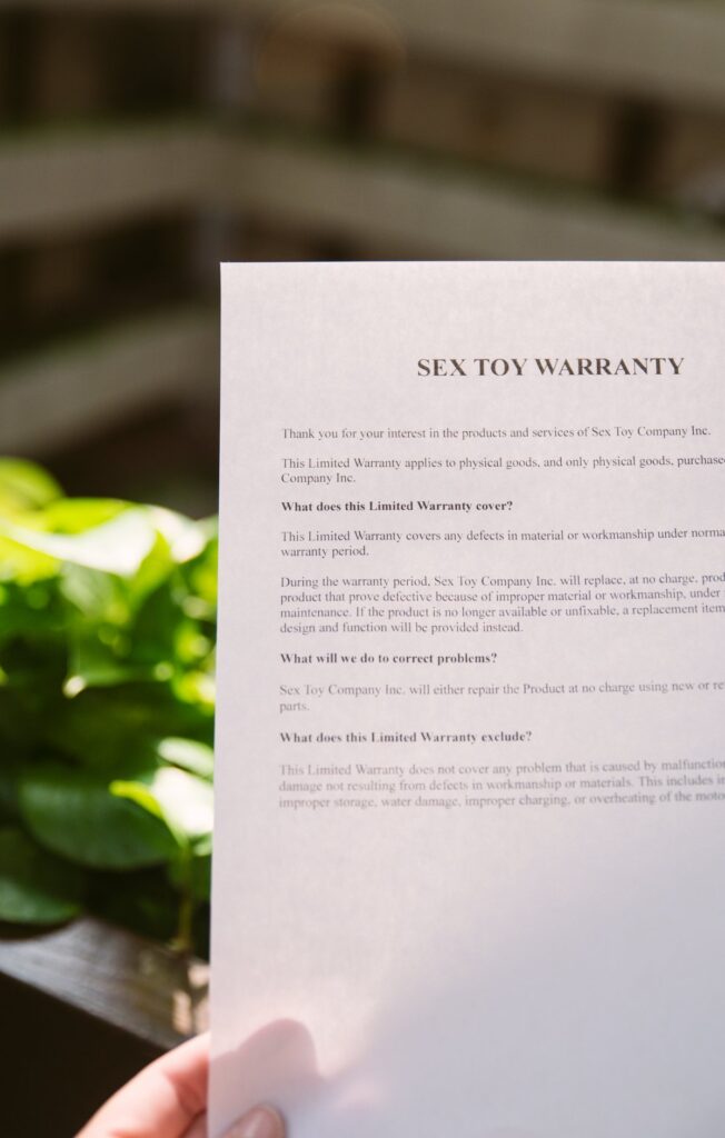I hold a piece of paper up in an atrium as bright, natural light filters in. The top of the paper reads "Sex toy Warranty" in big letters. For my How to submit a sex toy warranty article.