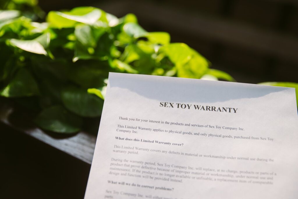 I hold a piece of paper up in an atrium as bright, natural light filters in. The top of the paper reads "Sex toy Warranty" in big letters. For my How to submit a sex toy warranty article.