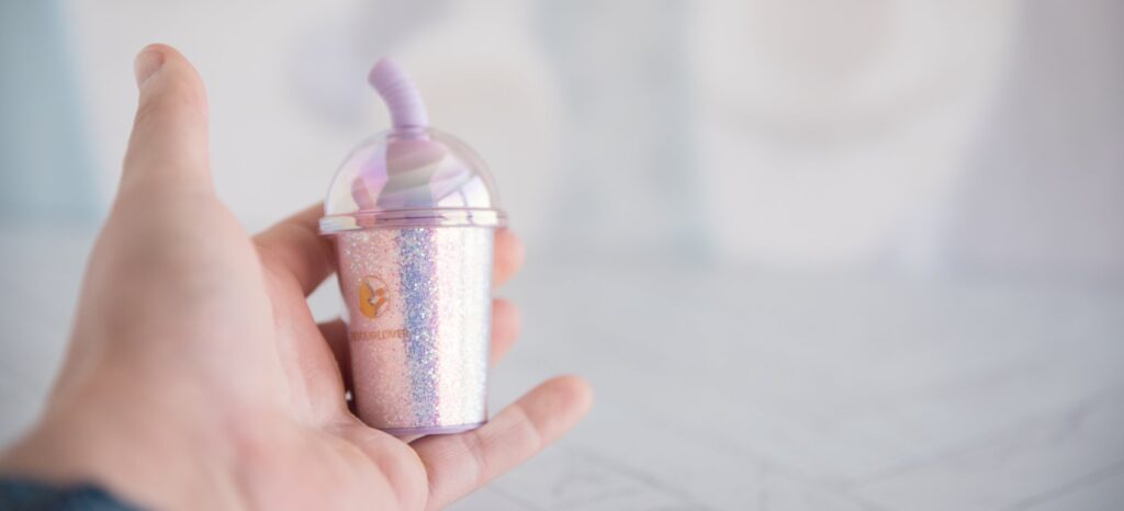 The vibrator is resting in my hand. It's very small - even smaller than my palm. It has a really cute little straw that looks even more adorable at this small size. For my BeYourLover Joy Cup review.