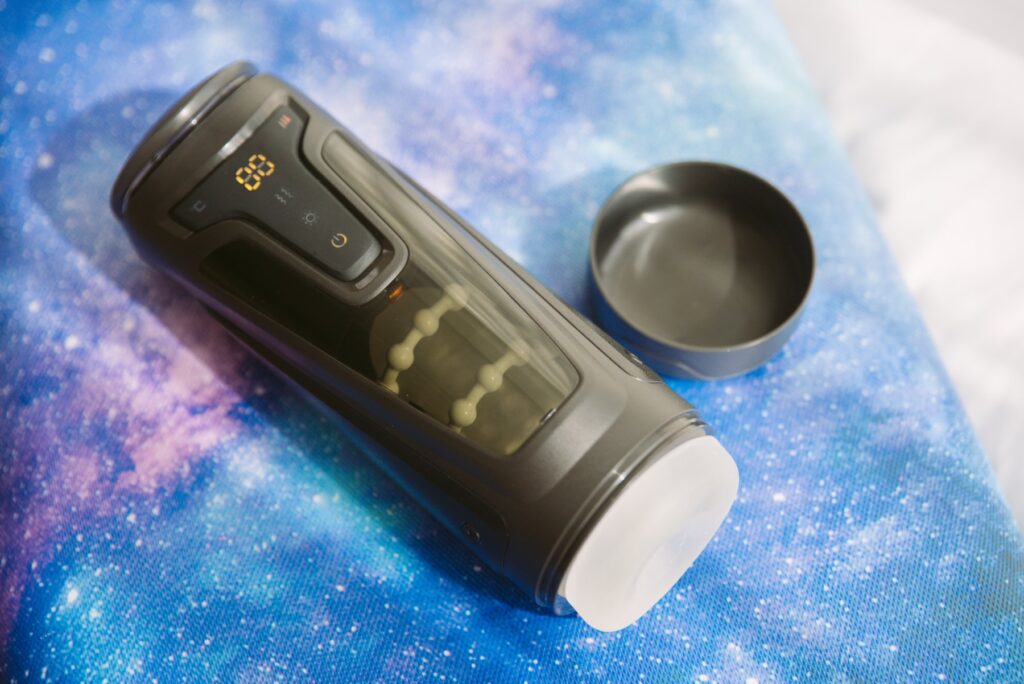 The penis stroker sits out on top of a galaxy-printed background to showcase its futuristic aspects. For my Fleshy Thrust Sync Review.