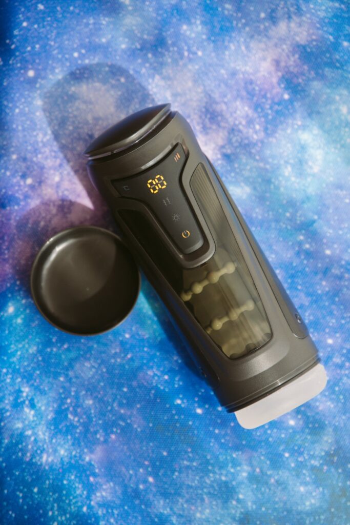 The penis stroker sits out on top of a galaxy-printed background to showcase its futuristic aspects. For my Fleshy Thrust Sync Review.