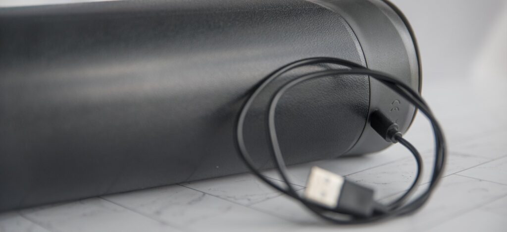 The charging cable plugged into the Fleshy Thrust Sync, showcasing its spot on the upper backside to plug it in.