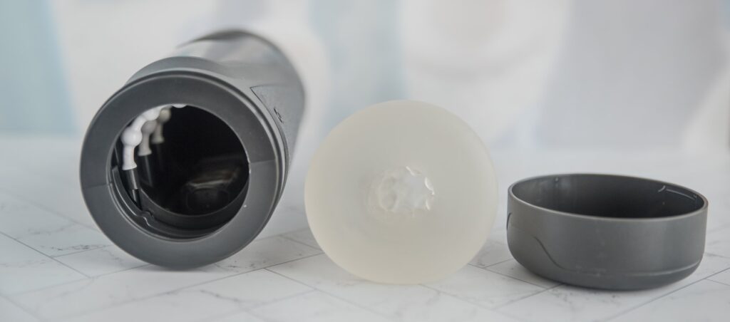 The TPE sleeve is removed from the Fleshy Thrust Sync and shown next to the cap, showcasing how all of the pieces fit together. For my Fleshy Thrust Sync Review.