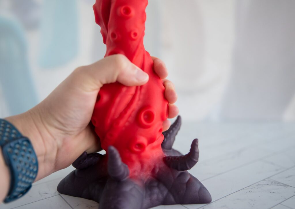 My hand is wrapped around the dildo's shaft. It's in the middle. The middle is thick, and my fingers can't meet when trying to wrap around the middle.