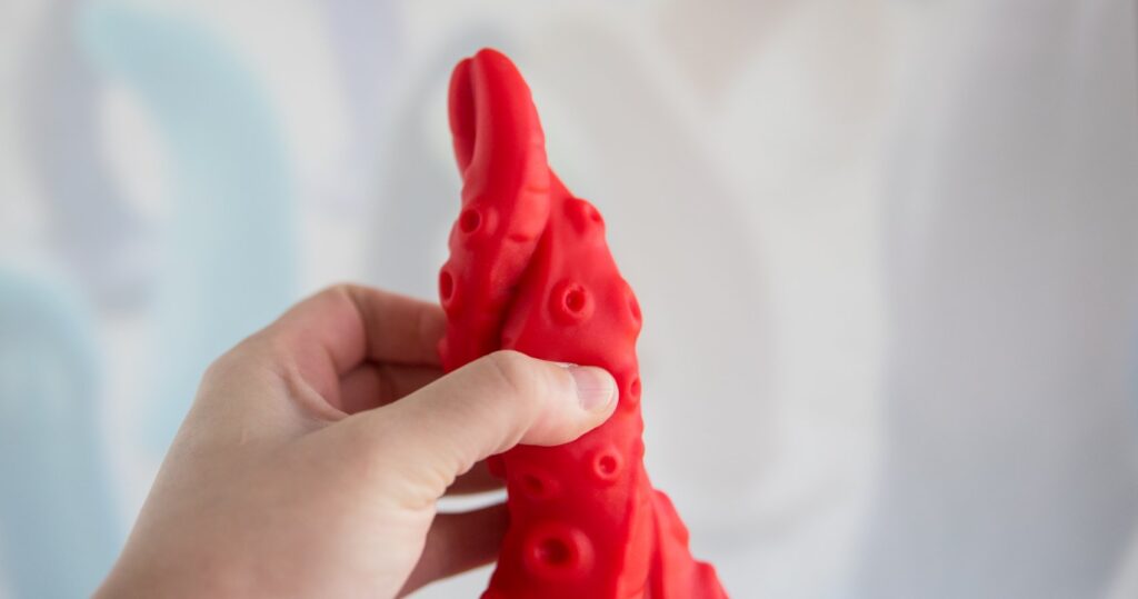My hand is wrapped around the dildo's shaft at the tip. It looks extremely slender - much smaller than average dildos. It gets thicker pretty quickly right after the tip though.