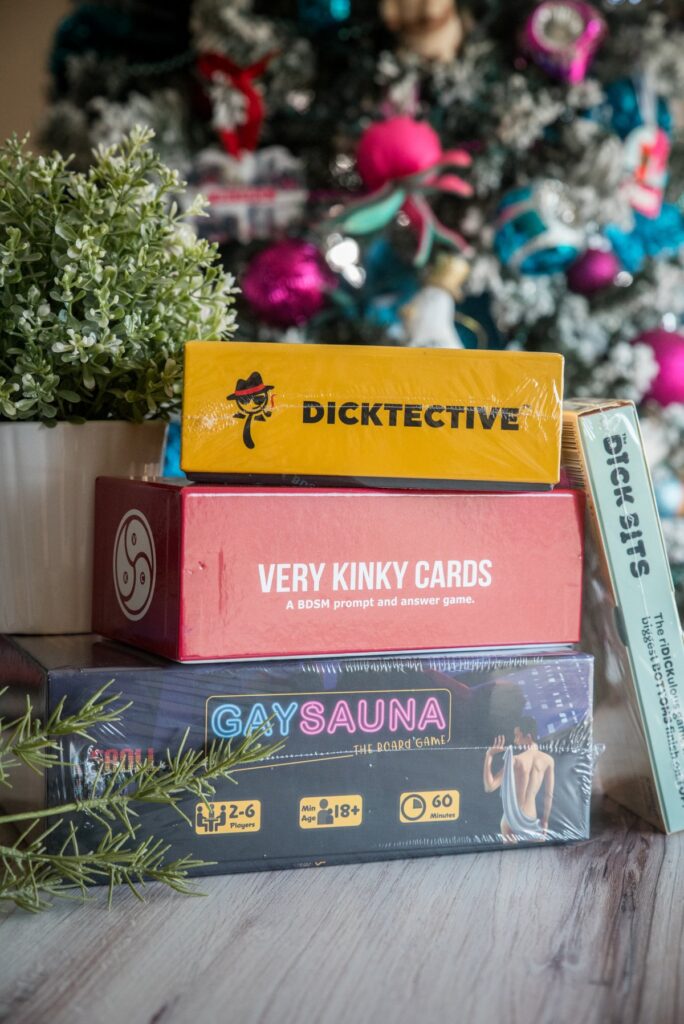 A stack of adult-theme board games are all stacked up. Some of them are still in the plastic wrap. For my article about kinky board games with friends that don't require sexual interaction.