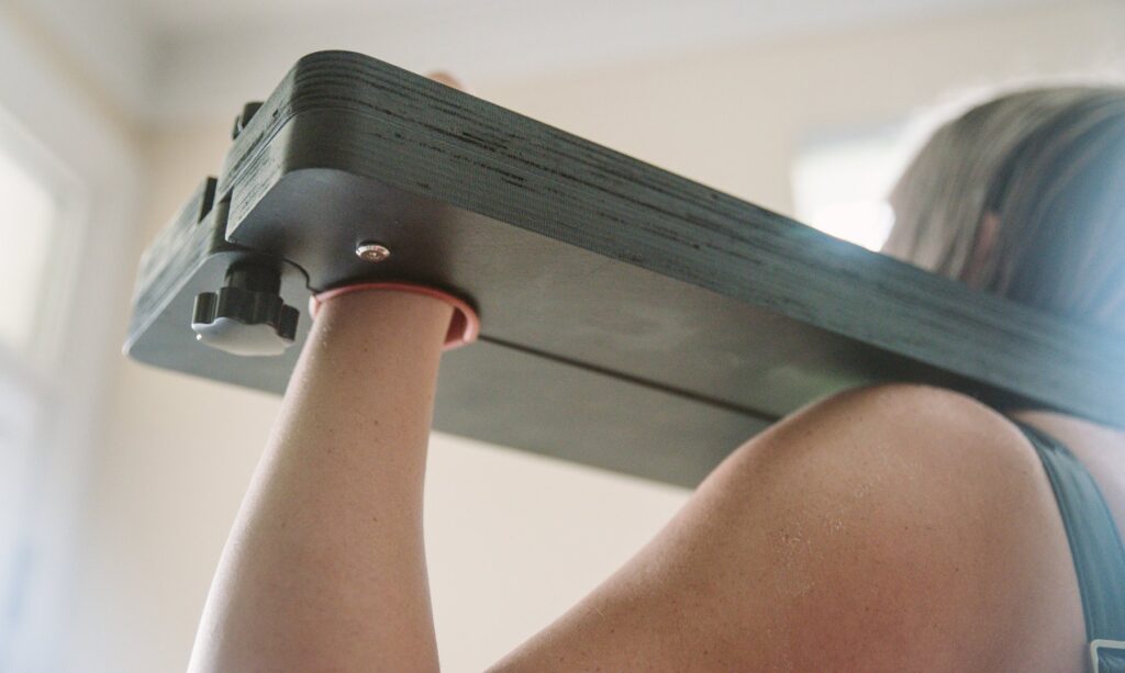Close-up of my partner's hand inside of the stockade, showcasing the twist-dials at the end of the stockade that allow for easy opening and closing to place a person inside.