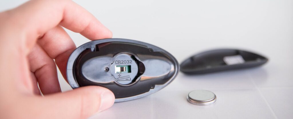 The underside of the remote with the battery compartment door open. This showcases that it uses a button cell battery to power the remote.