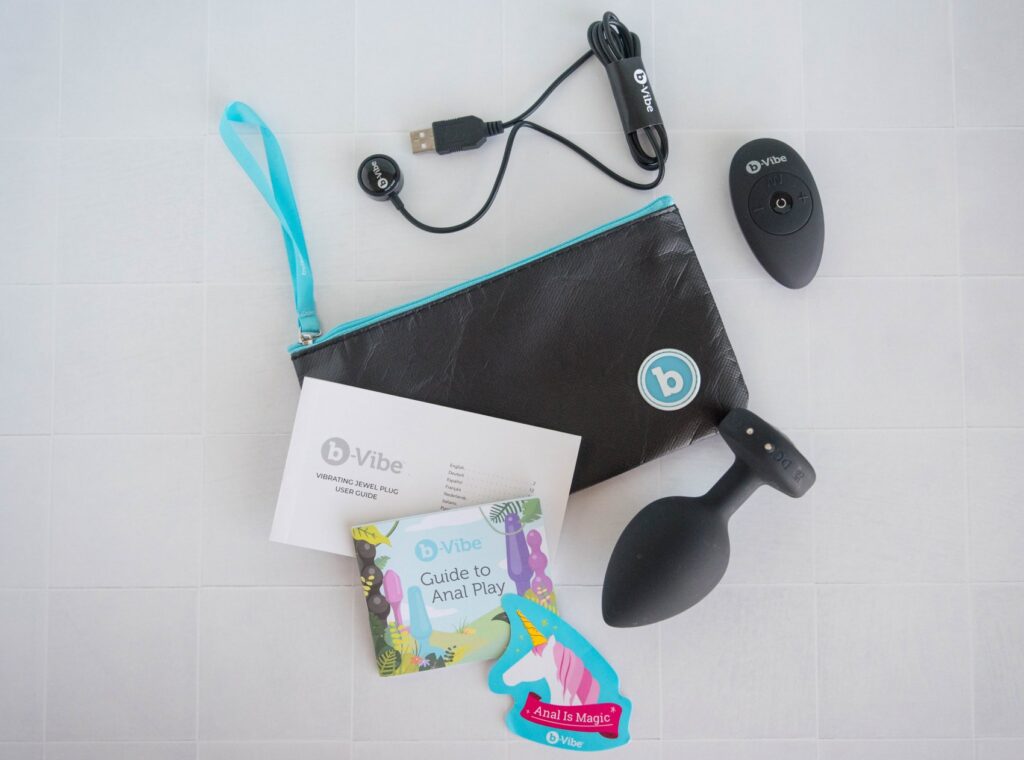 Everything that comes with the b-Vibe toy. There's the toy, the remote, the storage bag, the instruction manual, a sticker, the charging cord. For my b-Vibe XXL Vibrating Jewel Plug Review.