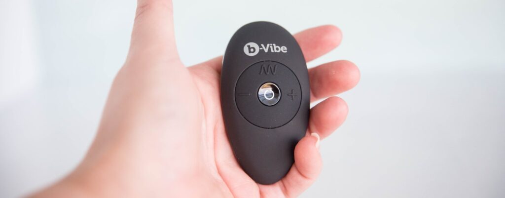 The wireless remote control held in my hand. The control is oval-shaped and hides in my palm with four different buttons on it to control the vibrations.