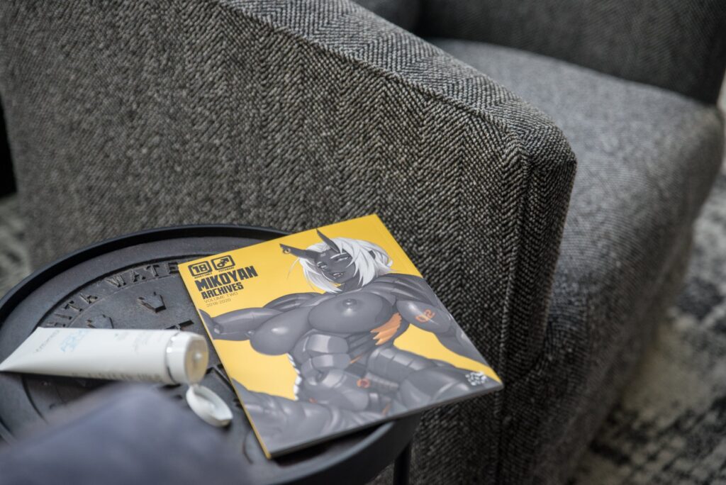 An adult magazine is laying out next to an opened bottle of lube. For my Femdom Goon Scene Ideas article.