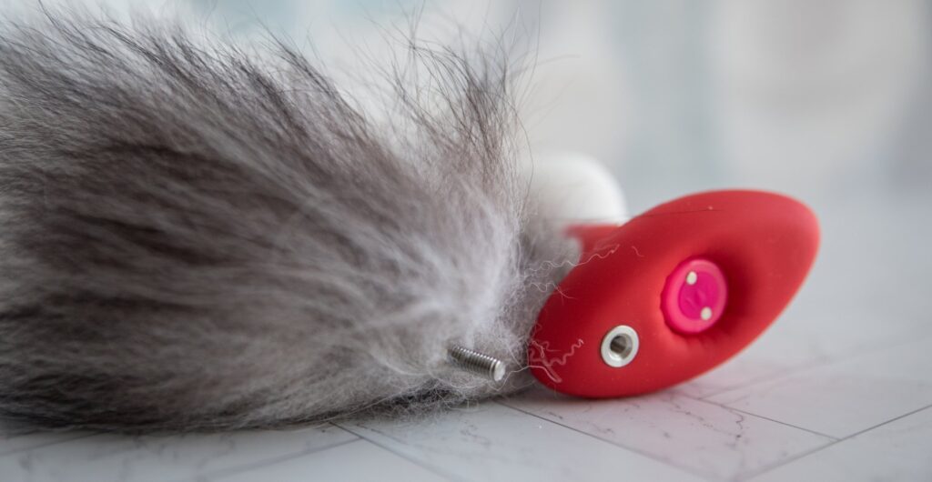 Close up on the base of the tail. The end of the tail features a literal screw that screws into the screw port on the base of the plug. The screw port is shown next to the screw of the tail.