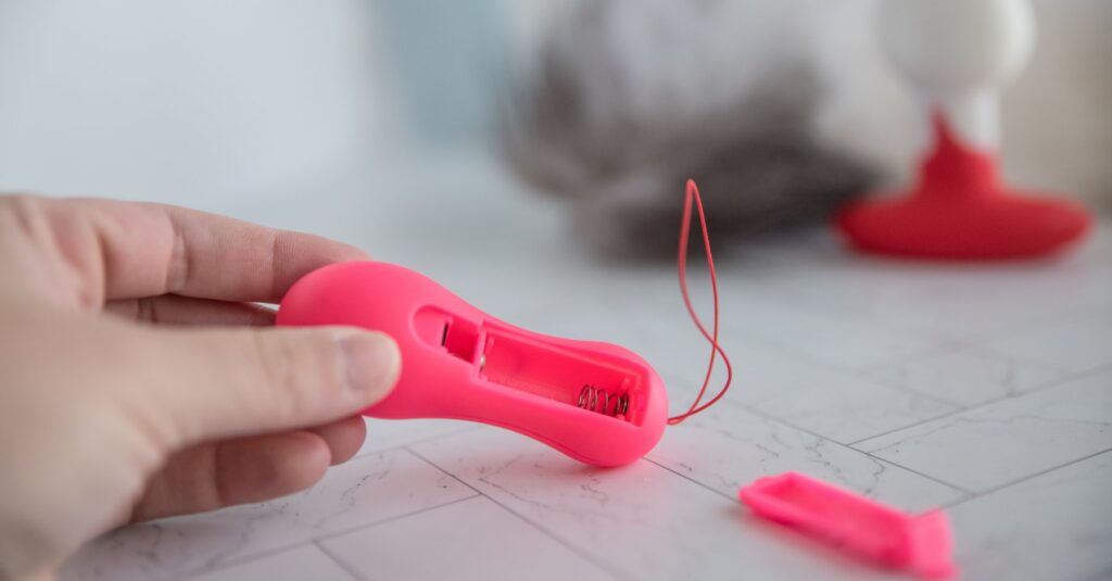 The backside of the remote control. The battery compartment cap is removed, showcasing the battery compartment open. It uses a non-standard battery.