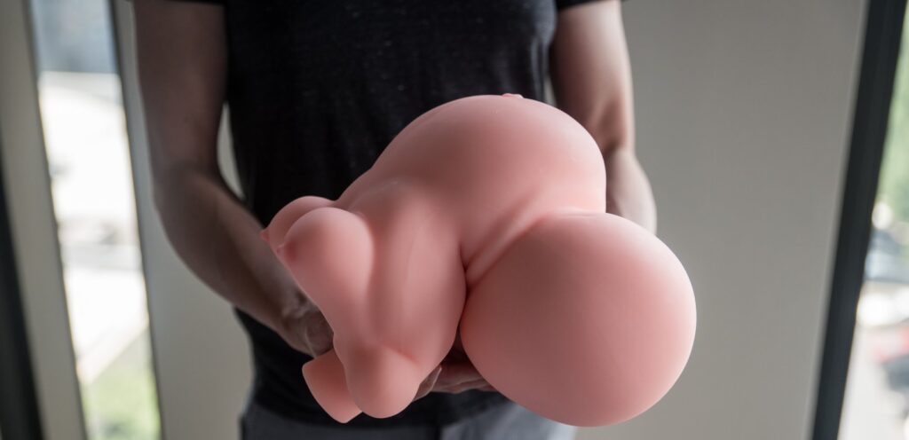 A person holds both ends of the Marissa sex doll. They are squishing and bending the doll into a weird form that doesn't look natural, showcasing how flexible and wiggly the material can be bent. For my MRLSexDoll Marissa review.