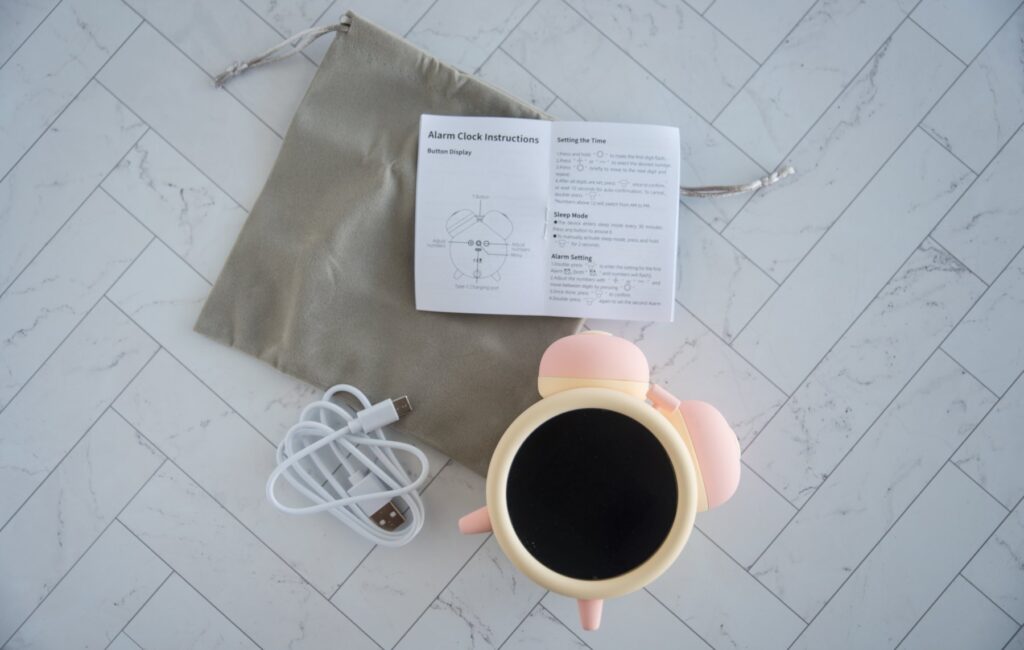 The BeYourLover Naughty Alarm Clock is laid out on a flat surface with everything it includes. There's the charging cable, instructions, and drawstring storage bag. For my BeYourLover Naughty Alarm Clock review.