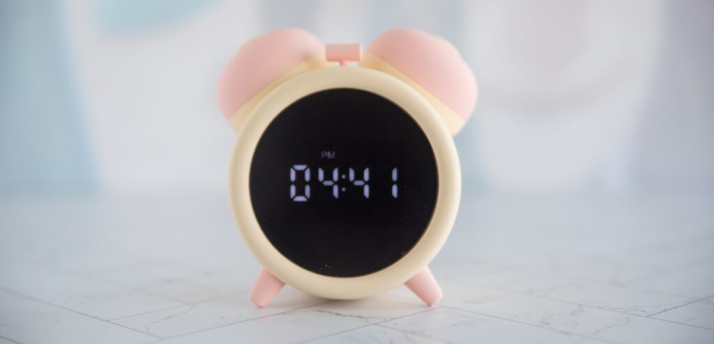 The alarm clock sex toy sitting out, with the time displaying and both toys resting inside of the clock's holster.