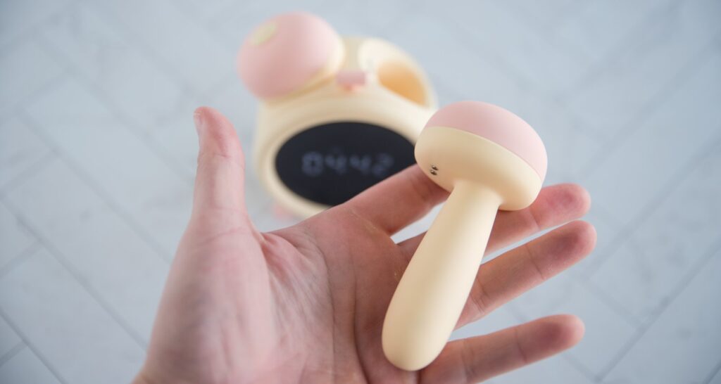 My hand holds the insertable vibrator that is one of the two toys included with the clock. It looks very short, but it still looks long enough to be potentially insertable if desired. For my BeYourLover Naughty Alarm Clock review.